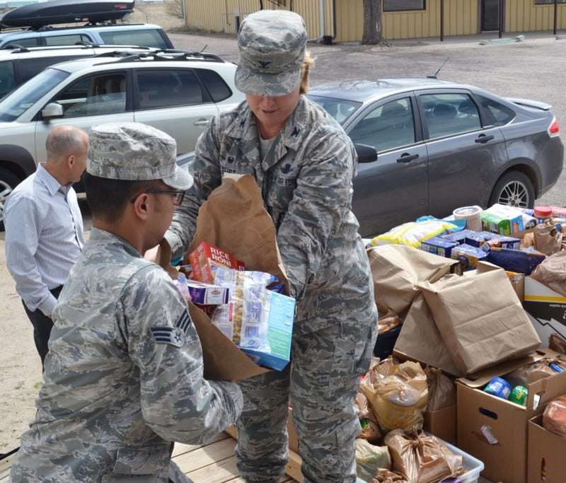 Col. DeAnna Burt, 50th Space Wing commander (right), transfers food to Senior Airman Matthew Sarangay, 50th Contracting Squadron, during a donation drop-off at the Ellicott Helping Hands Food Pantry in Ellicott, Colorado, Tuesday, April 26, 2016. 