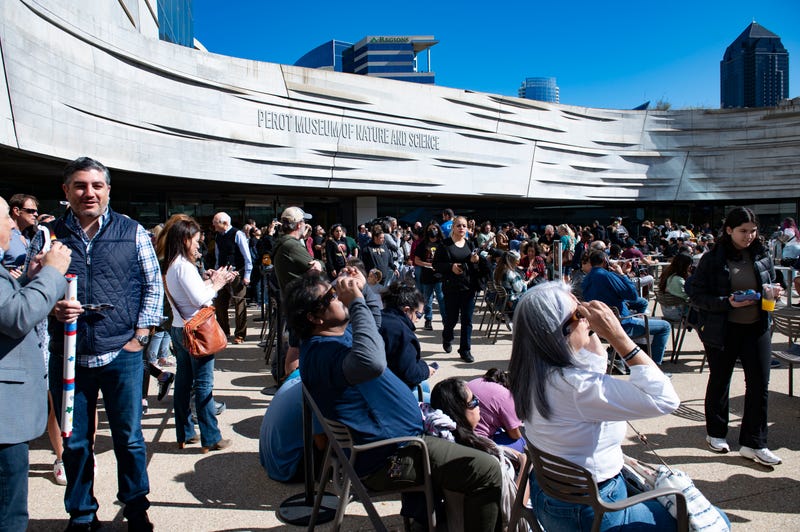 People with eclipse glasses at the Perot Museum of Nature and Science in Dallas, Texas.