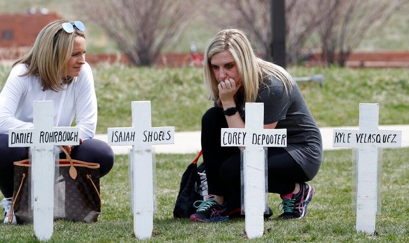 Cassandra Sandusky, right, a graduate of Columbine High School, pauses with her friend, Jennifer Dunmore, at a row of crosses bearing the names of the victims of the attack at the school 20 years ago before a program for the victims Saturday, April 20, 20