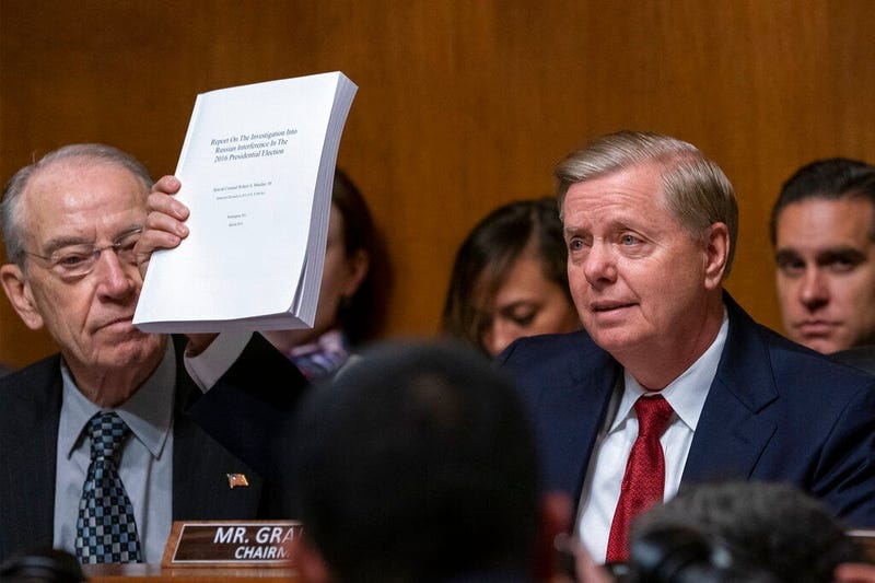 Senate Judiciary Committee Chairman Lindsey Graham, R-S.C., right, joined at left by Sen. Chuck Grassley, R-Iowa, raises a copy of Mueller report, during his opening statement before swearing-in Attorney General William Barr to testify, on Capitol Hill in