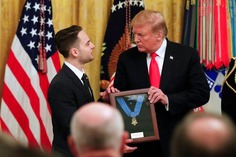 Trevor Oliver accepts the Medal of Honor from President Donald Trump, presented to his father, Army Staff Sgt. Travis Atkins in recognition for conspicuous gallantry in Iraq in June 2007, during a ceremony in the East Room of the White House, Wednesday Ma
