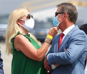 Georgia Gov. Brian Kemp has his mask adjusted by first lady Marty while waiting for President Donald Trump to arrive for his Georgia visit. (Curtis Compton/Atlanta Journal-Constitution via AP)