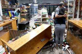 Yogi Dalal hugs his daughter Jigisha as his other daughter Kajal, left, bows her head at the family food and liquor store Monday, Aug. 10, 2020, after the family business was vandalized in Chicago. (AP Photo/Charles Rex Arbogast)