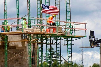 FILE - In this June 11, 2020 file photo, workers on scaffolding lay blocks on one of the larger buildings at a development site where various residential units and commercial sites are under construction. (AP Photo/Keith Srakocic, File)