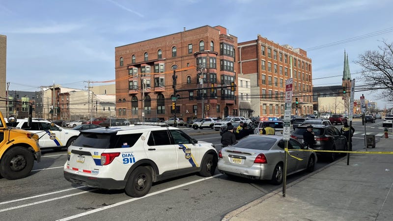 The scene on Spring Street Tuesday afternoon where, police say, people inside a pair of cars fired about a dozen shots as children were nearby with the school day ending.