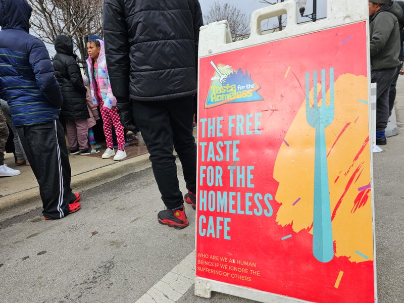 Taste for the Homeless sign with people behind it.