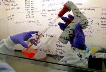 FILE - In this July 30, 2020 photo, Kai Hu, a research associate transfers medium to cells, in the laboratory at Imperial College in London. (AP Photo/Kirsty Wigglesworth)