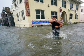 Trent Airhart wades through floodwaters, Wednesday, Sept. 16, 2020, in downtown Pensacola, Fla. (AP Photo/Gerald Herbert)