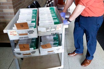 FILE - In this May 5, 2020, file photo, absentee ballots to be counted are moved at City Hall in Garden City, Mich. (AP Photo/Paul Sancya, File)