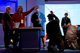 Members of the production crew inspect glass on stage which will serve as a barrier to protect the spread of COVID-19 as preparations take place for the vice presidential debate at the University of Utah in Salt Lake City.  (AP Photo/Julio Cortez)