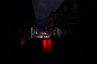 A passing car's headlights illuminate a darkened Bourbon Street in the French Quarter of New Orleans, Wednesday, Oct. 28, 2020. Hurricane Zeta passed through Wednesday leaving much of the city and metro area without power. (AP Photo/Gerald Herbert)