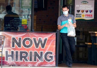 FILE - In this Sept. 2, 2020 file photo, a customer wears a face mask as they carry their order past a now hiring sign at an eatery in Richardson, Texas. (AP Photo/LM Otero, File)