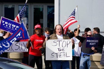 Supports of President Donald Trump holds signs during a demonstration outside the State Farm Arena where Fulton County has a voting counting operation, Thursday, Nov. 5, 2020, in Atlanta. (AP Photo/John Bazemore)