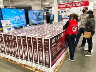 A sales associate helps customers as they consider the purchase of a big-screen television at a Costco warehouse on Wednesday, Nov. 18, 2020, in Sheridan, Colo. (AP Photo/David Zalubowski)
