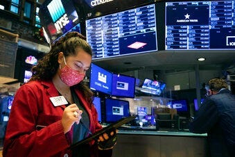 In this photo provided by the New York Stock Exchange, trader Ashley Lara uses her handheld device as she works on the trading floor, Tuesday, Dec. 1, 2020. (Colin Ziemer/New York Stock Exchange via AP)