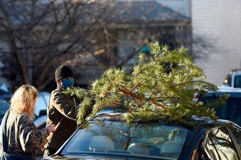 Parker Vivier and Marsden Olsen, both of Richmond, prepare to tie their tree to their car after purchasing from Frank Pichel's tree lot, Sunday, Dec. 6, 2020, in Richmond. (AP Photo/Will Newton)