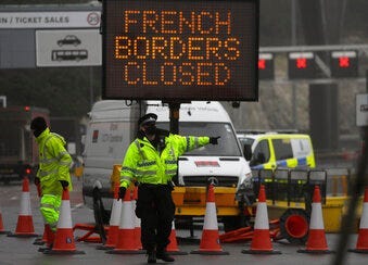 A police officer directs traffic at the entrance to the closed ferry terminal in Dover, England, Monday, Dec. 21, 2020. (AP Photo/Kirsty Wigglesworth)