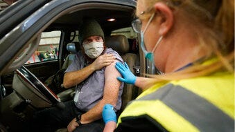 Spencer Jensen, music teacher at the Legacy Preparatory Academy receives the COVID-19 vaccine at the Davis County Legacy Center Tuesday, Jan. 12, 2021, in Farmington, Utah. (AP Photo/Rick Bowmer)