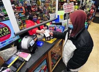 Jacqueline Donahue of Hazleton, right, buys la Mega Millions lottery ticket at the Anthracite Newsstand on Public Square, Monday, Jan. 18, 2021, in Wilkes-Barre, Pa. (Mark Moran/The Citizens' Voice via AP)