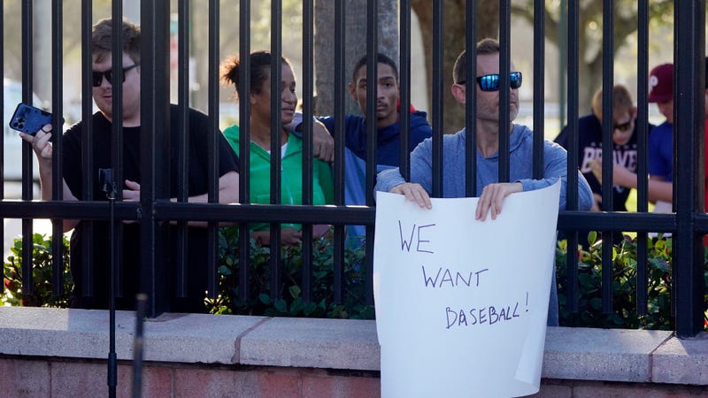 Baseball fans watch as Major League Baseball Commissioner Rob Manfred speaks during a news conference