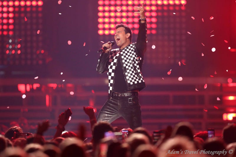 Man on stage holding microphone with fist in the air