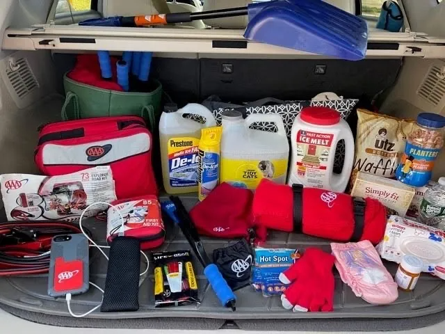 A car trunk packed with items recommended for an emergency travel kit.
