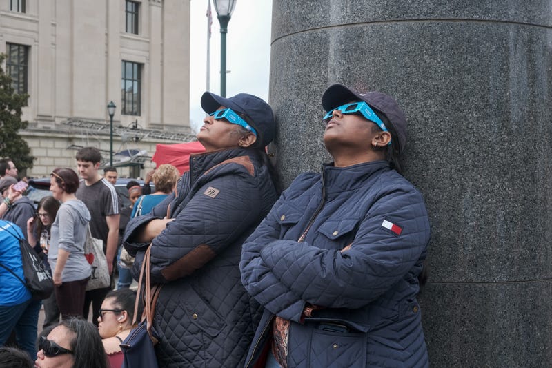 Two women look up at the near total solar eclipse over Philadelphia on April 8, 2024.