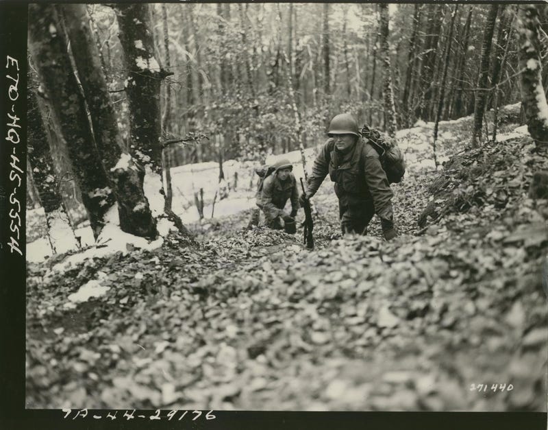 Elements of CO. B, 1st Bn., 157th Infantry Regiment, 45th Division, march into a new position in the woods above Zinswiller, France, where fighting is heavy.