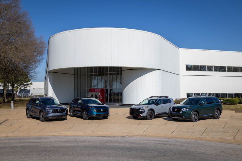 Four SUVs are parked in front of a modern white cylindrical building, under a clear blue sky. The scene conveys a sense of technology and innovation.