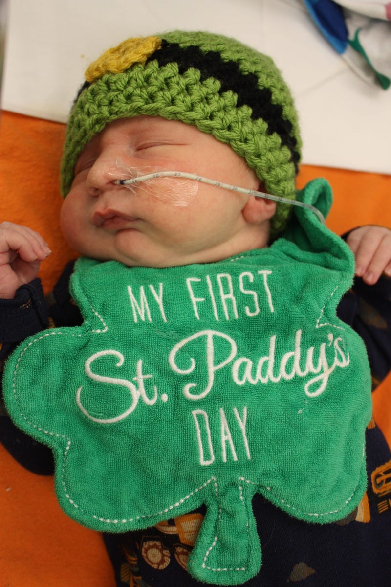 Newborn wearing St. Patrick's Day bib and hat
