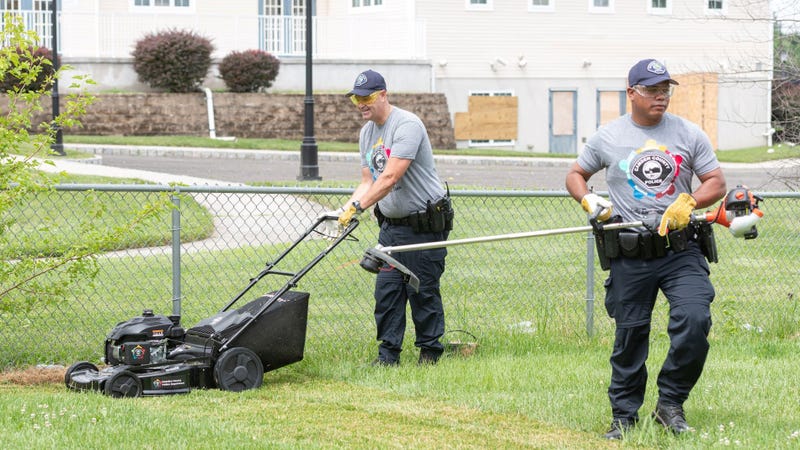 Camden County Police officers working on seniors' lawns on July 7, 2022.