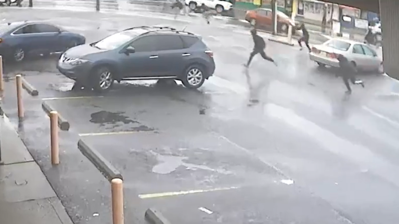 Three gunmen are seen in surveillance video Wednesday running toward their getaway car, where a fourth suspect, the driver, waits to take them away.