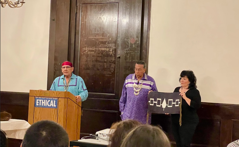 Jake Edwards (at the podium), Onondaga Chief, Tadodaho Sid Hill and Betty Lyons holding the Hiawatha Belt, the national belt of the Haudenosaunee, on Nov. 20, 2024, at the New York Society for Ethical Culture.