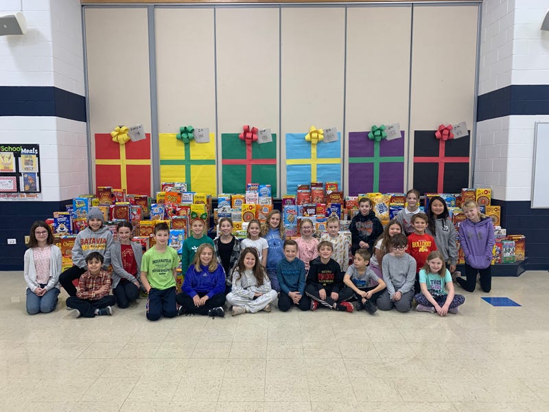 Students pose next to donated cereal boxes