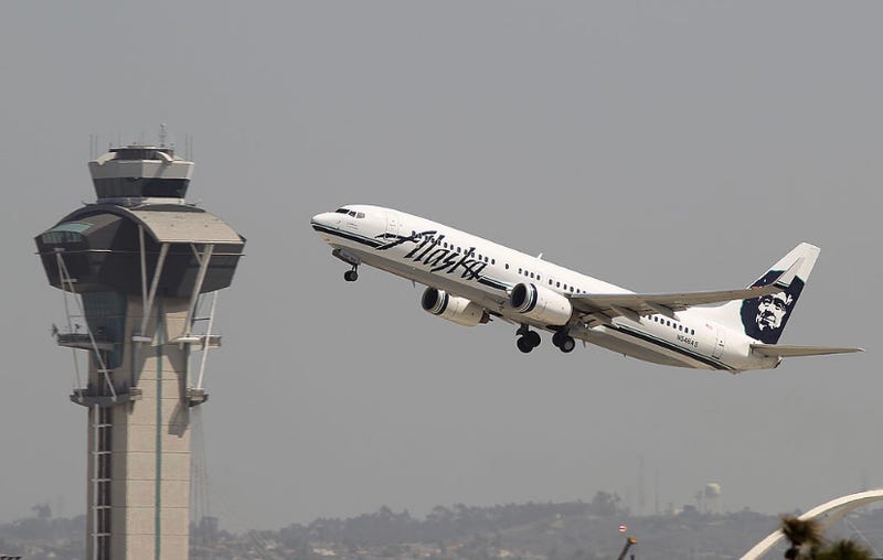 An Alaska Airlines jet passes the air traffic control tower at LAX.