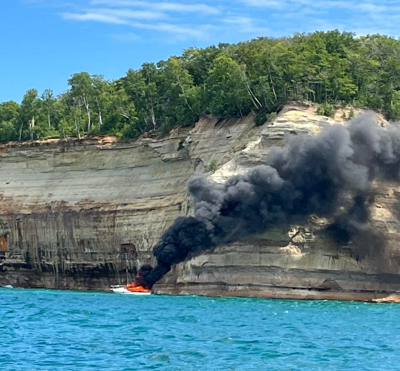 Burning boat in waterside cliffs 