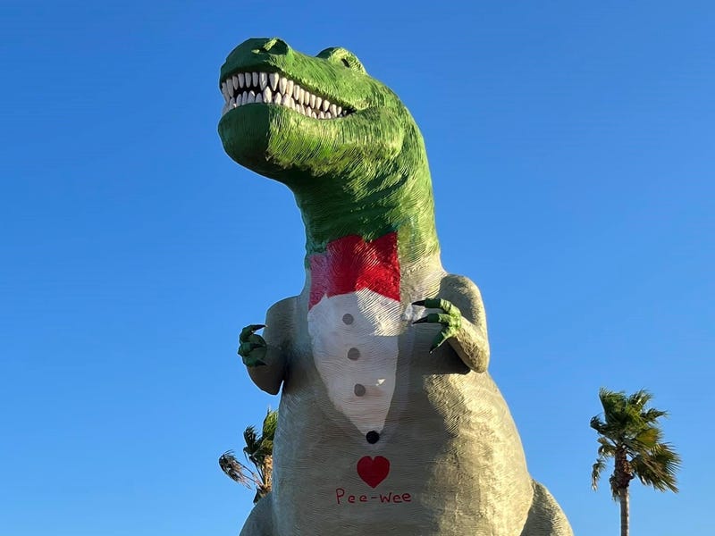 dinosaur statue painted to look like it's wearing a gray suit and red tie
