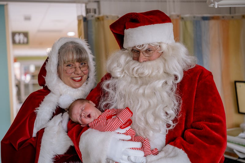 Santa, Ms. Claus holding baby in striped onesie