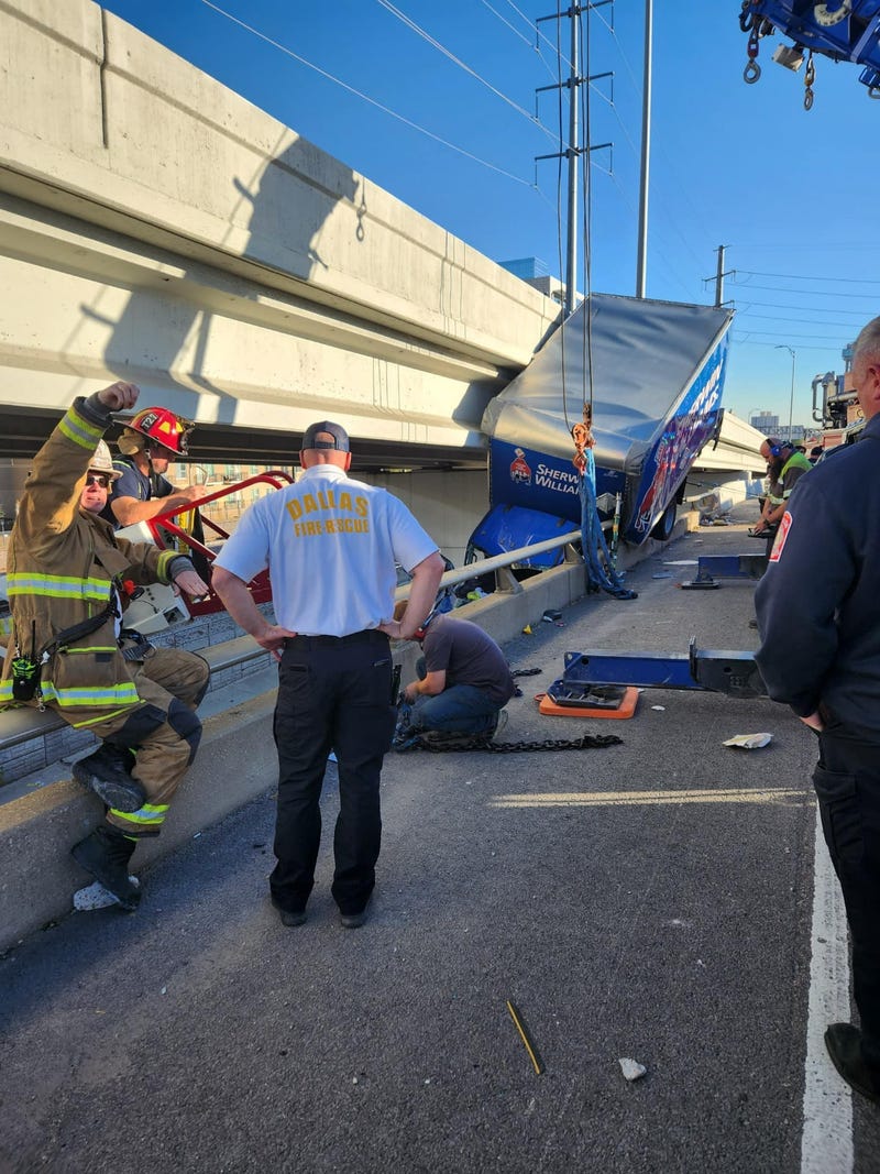 A Sherwin Williams truck hangs off a highway on Interstate 35E in Dallas on Monday, Dec. 4, 2023.