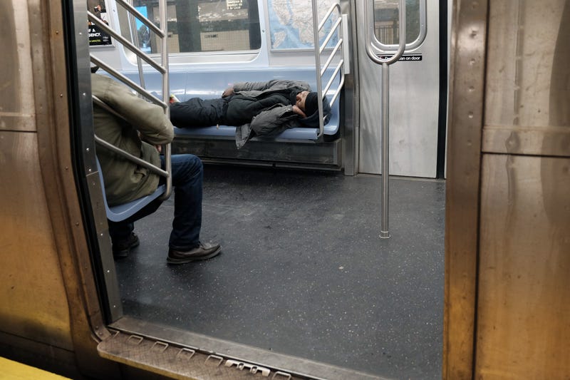 A man sleeps in a subway car in New York.