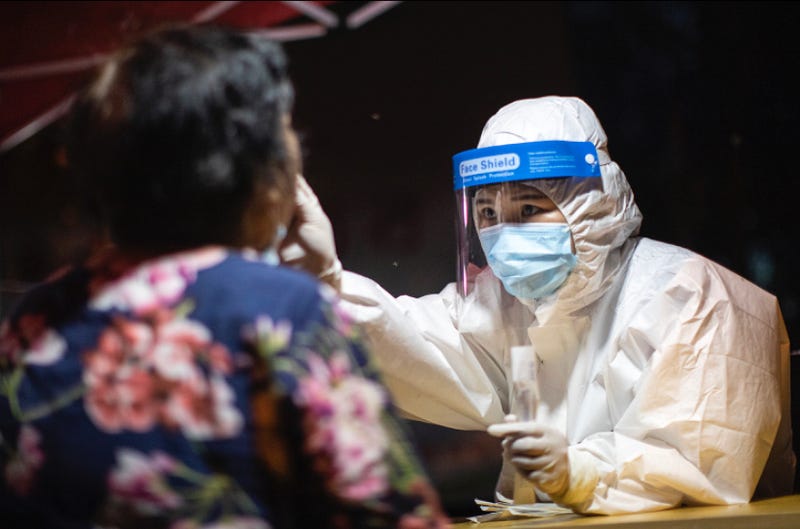 A medical worker takes samples during a mass Covid-19 test in a residential block in Wuhan, China.