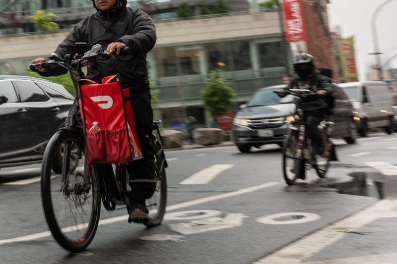 A delivery worker carries a DoorDash bag during a delivery in New York