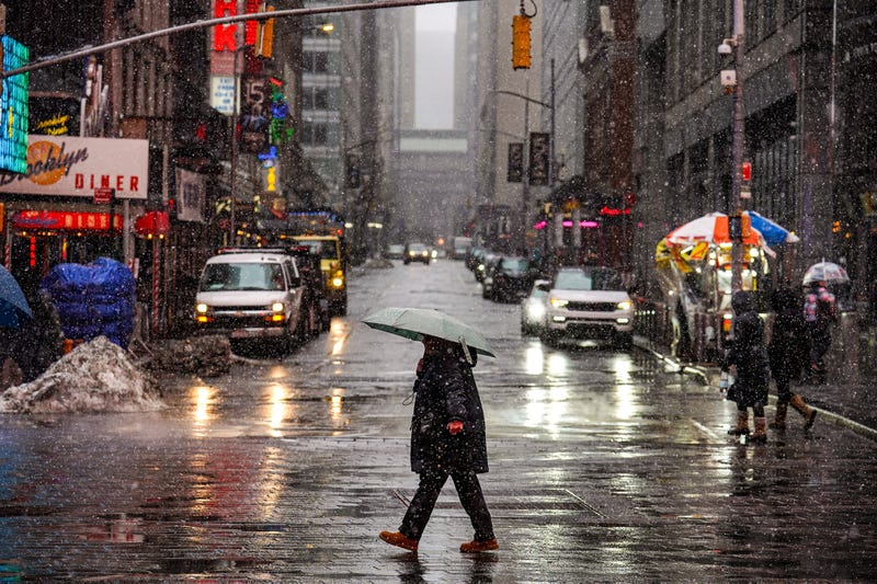 Pedestrians walk along the street as snow falls in New York on Feb. 22