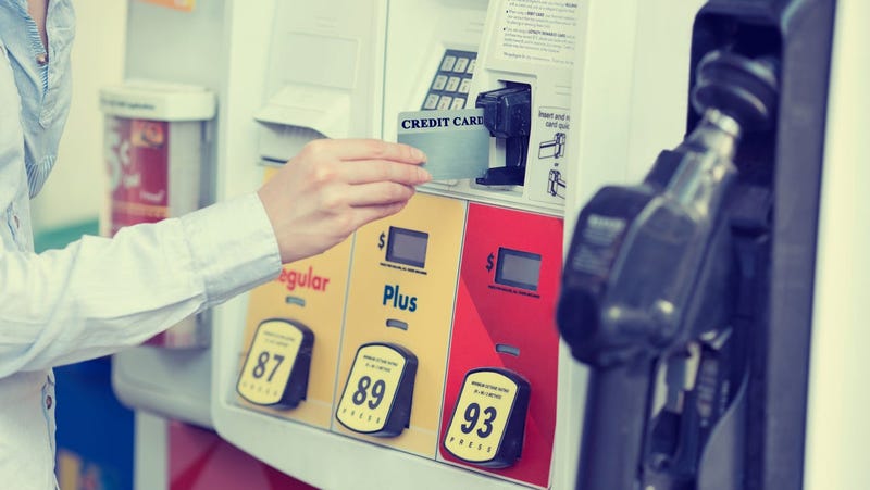 Woman hand swiping credit card at gas pump station