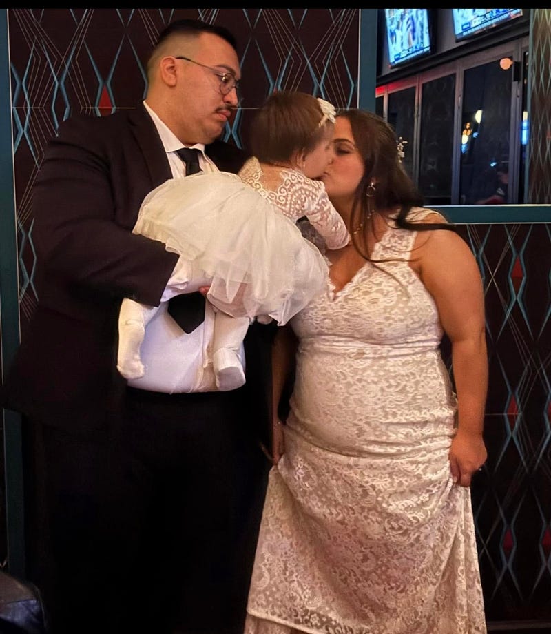 Man holding baby, woman kissing baby