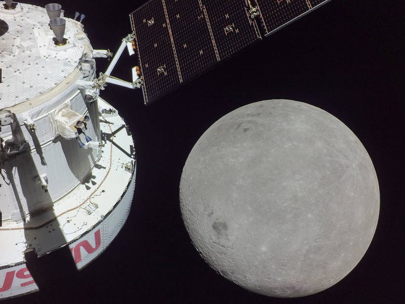 A portion of the far side of the Moon looms large just beyond the Orion spacecraft in this image taken Monday, Nov. 21, the sixth day of the Artemis I mission, by a camera on the tip of one of Orion’s solar arrays. The darkest spot visible near the middle of the image is Mare Orientale.