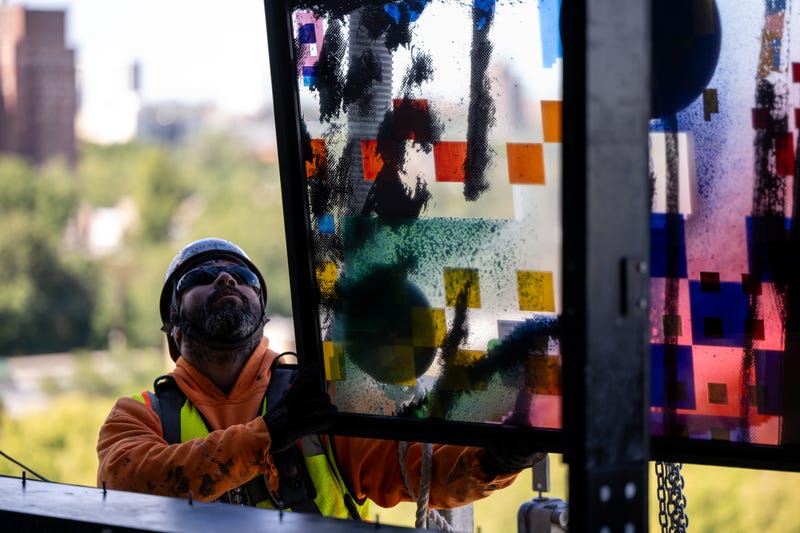 Crews work to install one of 35 stained glass panels for “Uprising of the Sun.”
