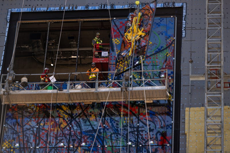 Crews work to install one of 35 stained glass panels for “Uprising of the Sun.”