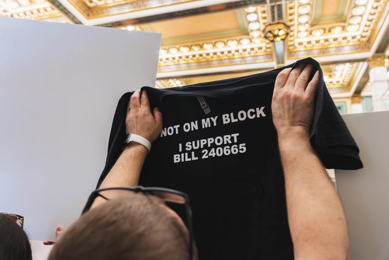 A supporter of the bill limiting mobile service providers holds up a shirt in City Council on Thursday, May 8, 2025.