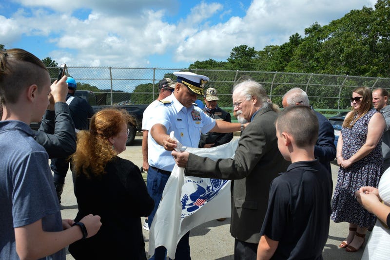 Coast Guard Adm. Andy Tiongson presents Stephen and Bradley Finch with the Coast Guard Ensign